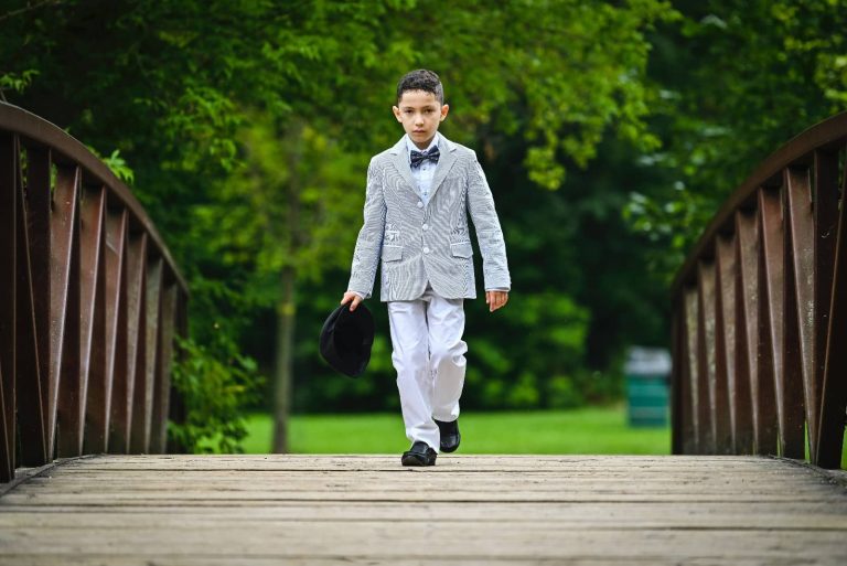 Niño con traje de comunión caminando por un puente de madera