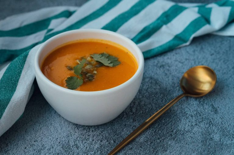 Cuenco de crema fría con hierbas y una cuchara dorada