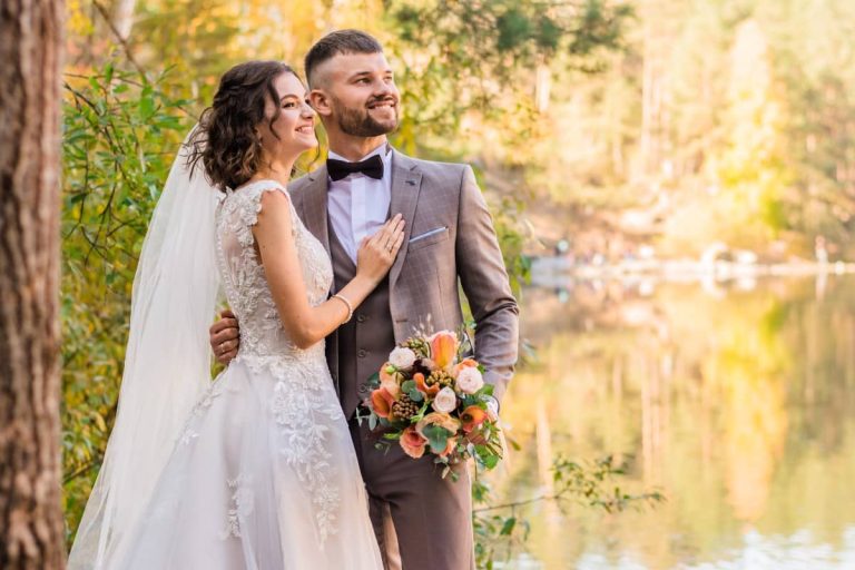 Novios sonriendo junto a un lago