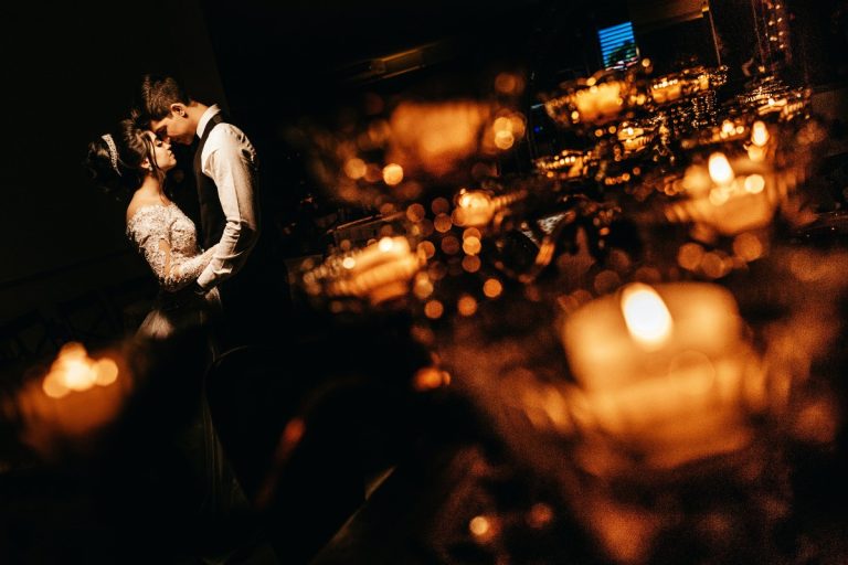 Novios besándose de noche entre luces de velas