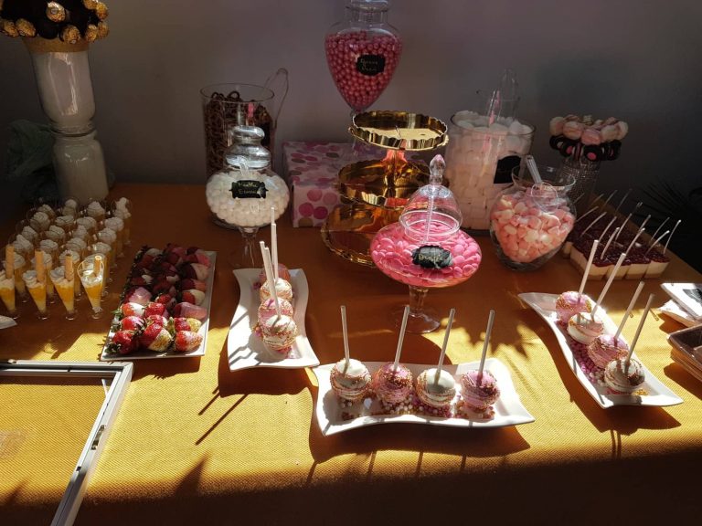 Mesa dulce con piruletas de bizcocho, fresas y tarros de golosinas