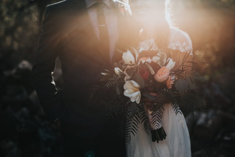 Novios a contraluz con un ramo de flores