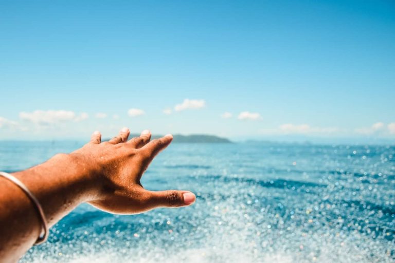 Mano extendida hacia el mar desde una barca