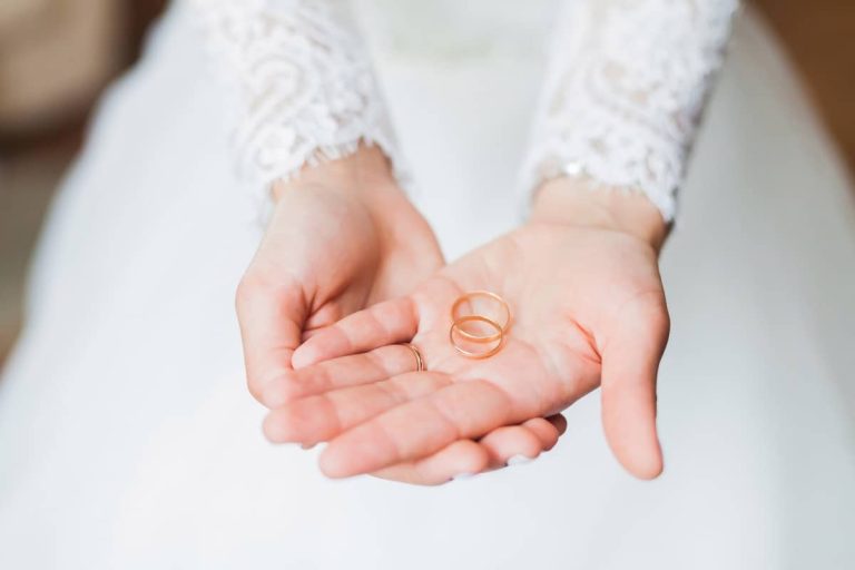 Manos de la novia sosteniendo las dos alianzas
