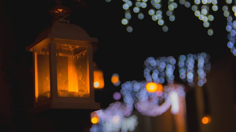 Farol encendido de noche con luces de fondo