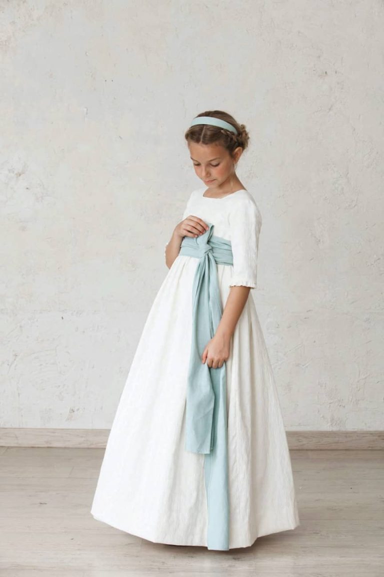 Niña con vestido de comunión blanco y fajín azul