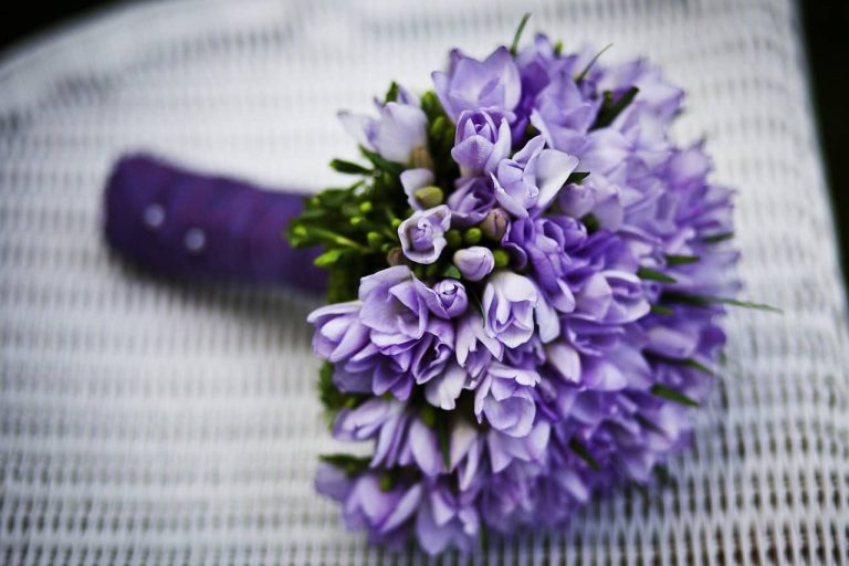 Ramo de novia de flores lilas sobre un asiento blanco